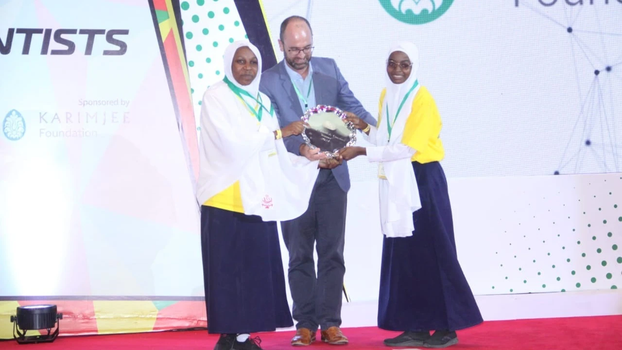 Karimjee Foundation's Head of Marketing, Cobus Van Zyl (C), presents a trophy to the overall winners of the Young Scientists Tanzania (YST) National Exhibition 2024.