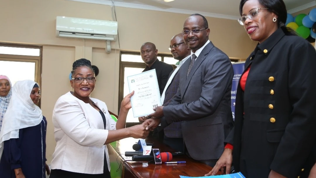 Ilala district commissioner Edward Mpogolo (2nd-R) presents a certificate in Dar es Salaam on Thursday to one of the women entrepreneurs who have recently free training conducted by the College of Business Education. 