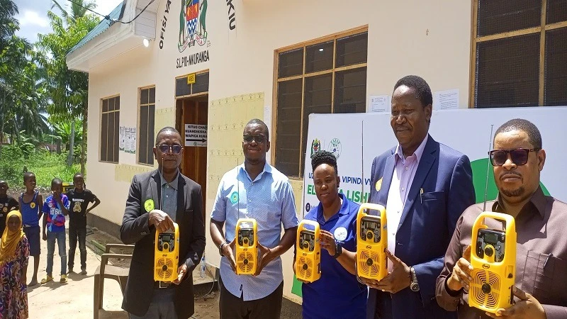 Shedrack Mziray, TASAF Executive Director (1st L); Omary Mwanga, Mkuranga District Administrative Secretary; Rose Kimaro (C), UNICEF Deputy Representative for Operations (2nd R); display radios to be distributed to TASAF beneficiaries .