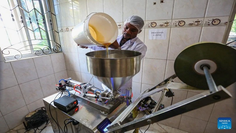 Jackson Mponela, production manager for commerce and development at Tanzania Future Enterprises Company Limited, prepares to package honey in bottles at a factory in Dar es Salaam, Four employees of a honey processing company located at Goba, 18 kilometer