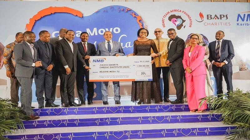 Former President Jakaya Kikwete (C) receives a dummy cheque worth 1bn/- from NMB Bank’s Chief Executive Officer, Ruth Zaipuna during a fundraising dinner aimed at supporting heart treatment for underprivileged children treated by the JKCI institute in Dar