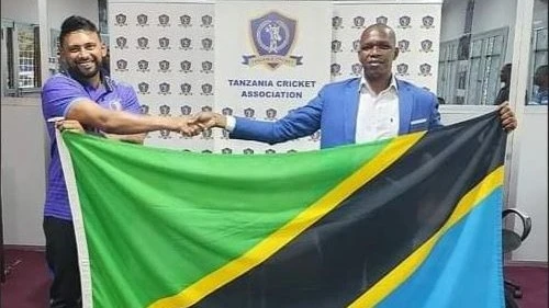 National Sports Council (NSC) Sports Officer Charles Maguzu (R) hands over the national flag to Tanzania's senior men's cricket team skipper Abhik Patwa at an occasion for bidding the team farewell in Dar es Salaam last Saturday