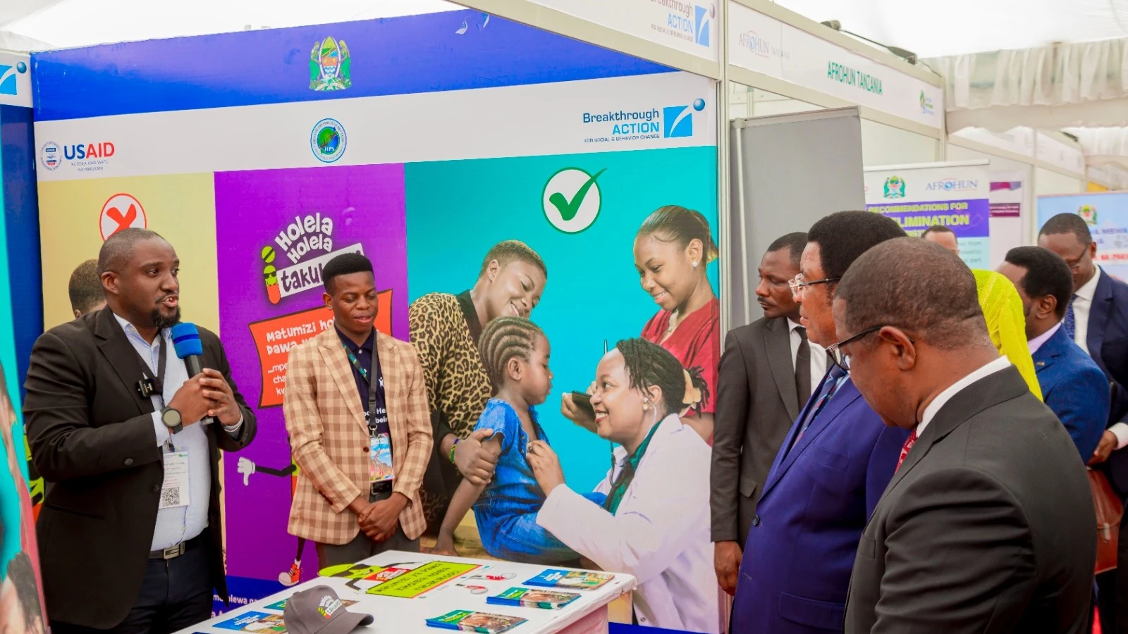 Prime Minister, Kassim Majaliwa gets a briefing from USAID Breakthrough ACTION Program Manager Mark Lwakare when he visited their exhibition booth during the Tanzania one health conference held in Arusha Region recently. 