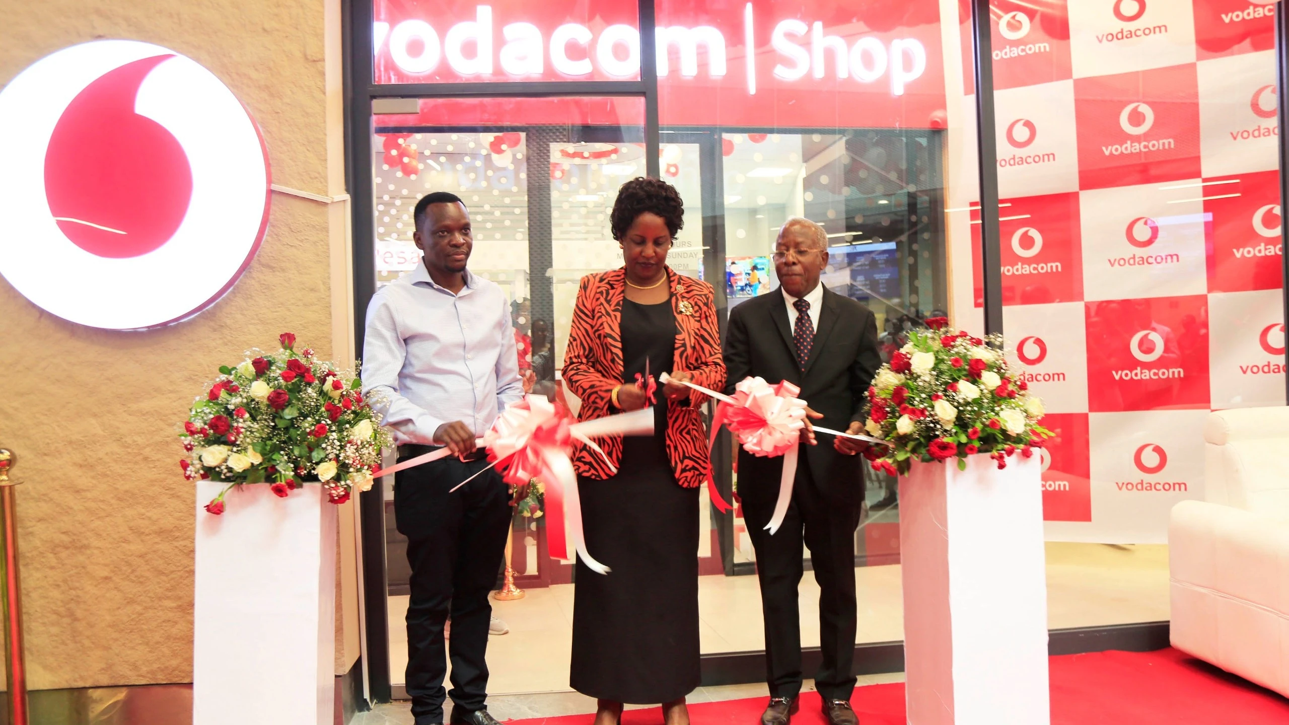 Dodoma Regional Commissioner Rosemary Senyamule cuts the ribbon to officially open the Vodacom store at Samia SGR station. She was joined by Vodacom Board Chairman, retired Judge Thomas Mihayo (right), and business partner Emmanuel Makaki (left).