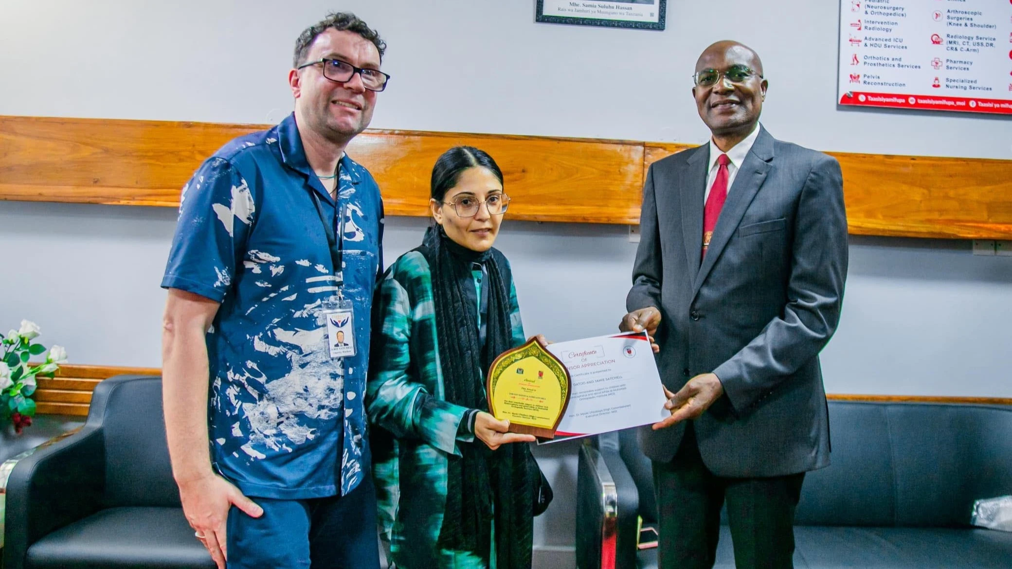 Dr Mpoki Ulisubisya (R), Executive Director of the Muhimbili Orthopaedic Institute (MOI), presents certificate of appreciation in Dar es Salaam yesterday to UK-based couple Zarnat Datoo and Jamie Satchell 