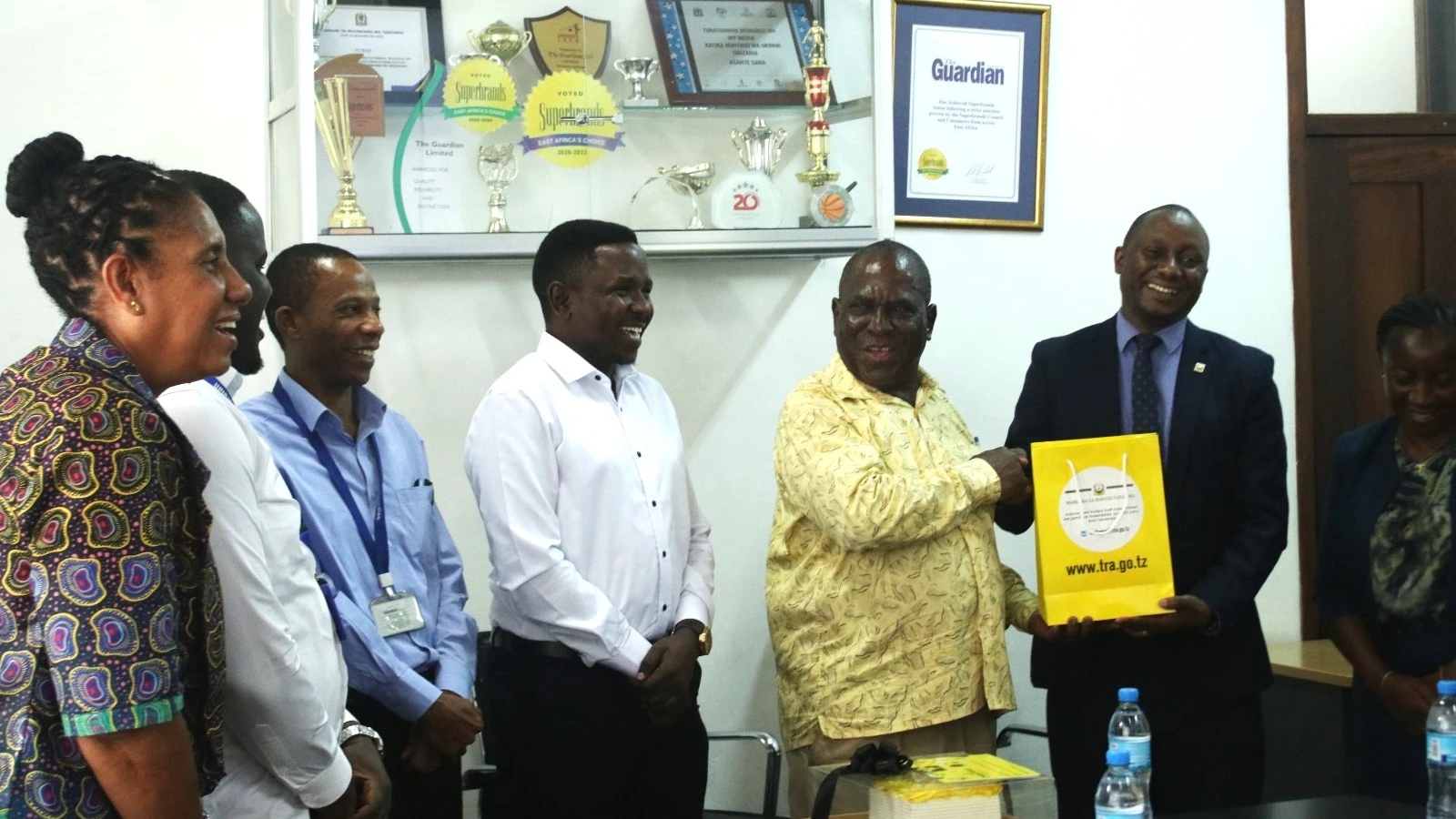 Paul Walalaze (R), Tanzania Revenue Authority Taxpayer Education Manager, presents a souvenir to The Guardian Limited’s Managing Editor Wallace Mauggo (2nd-R) in recognition of the company’s significant efforts in advancing tax awareness.