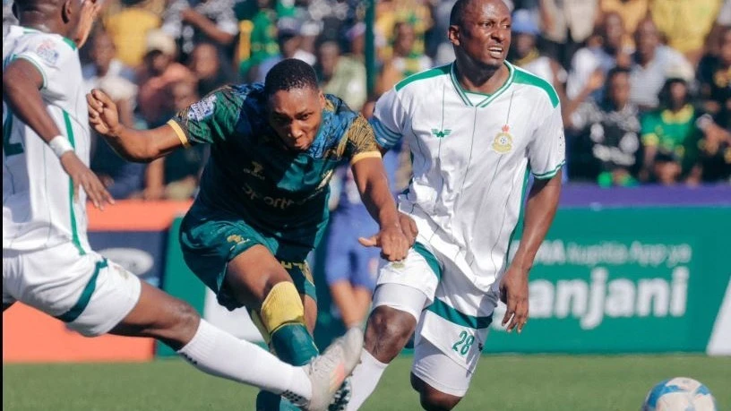 Young Africans striker Clement Mzize shoots past two Tanzania Prisons defender to score his side’s first goal during their Premier League match at KMC Complex yesterday. 