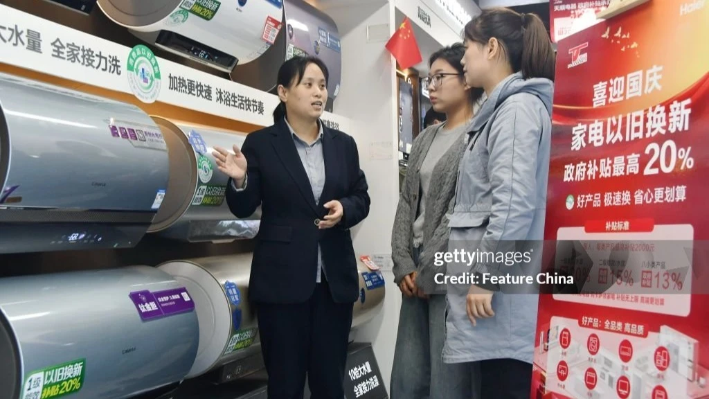 A sales agent talks to prospective customers at a home appliances store in Handan city in north China's Hebei province.