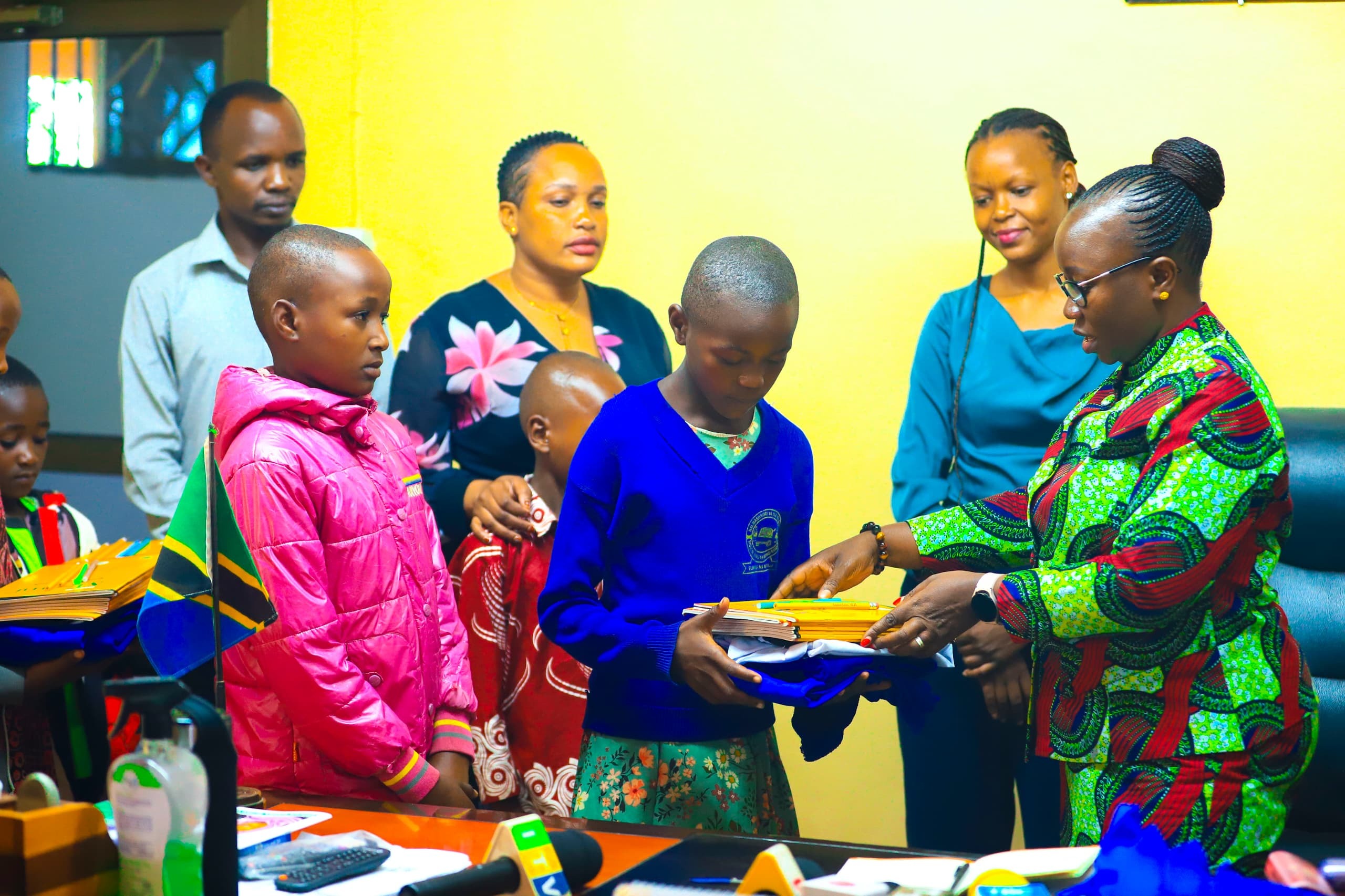 Babati District Commissioner in Manyara Region, Emmanuela Kaganda (R), hands over school supplies to students from underprivileged families in the district on Wednesday, to enabling them to return to school. 