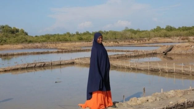 Salma Mahmoud Ali walks through her salt ponds.