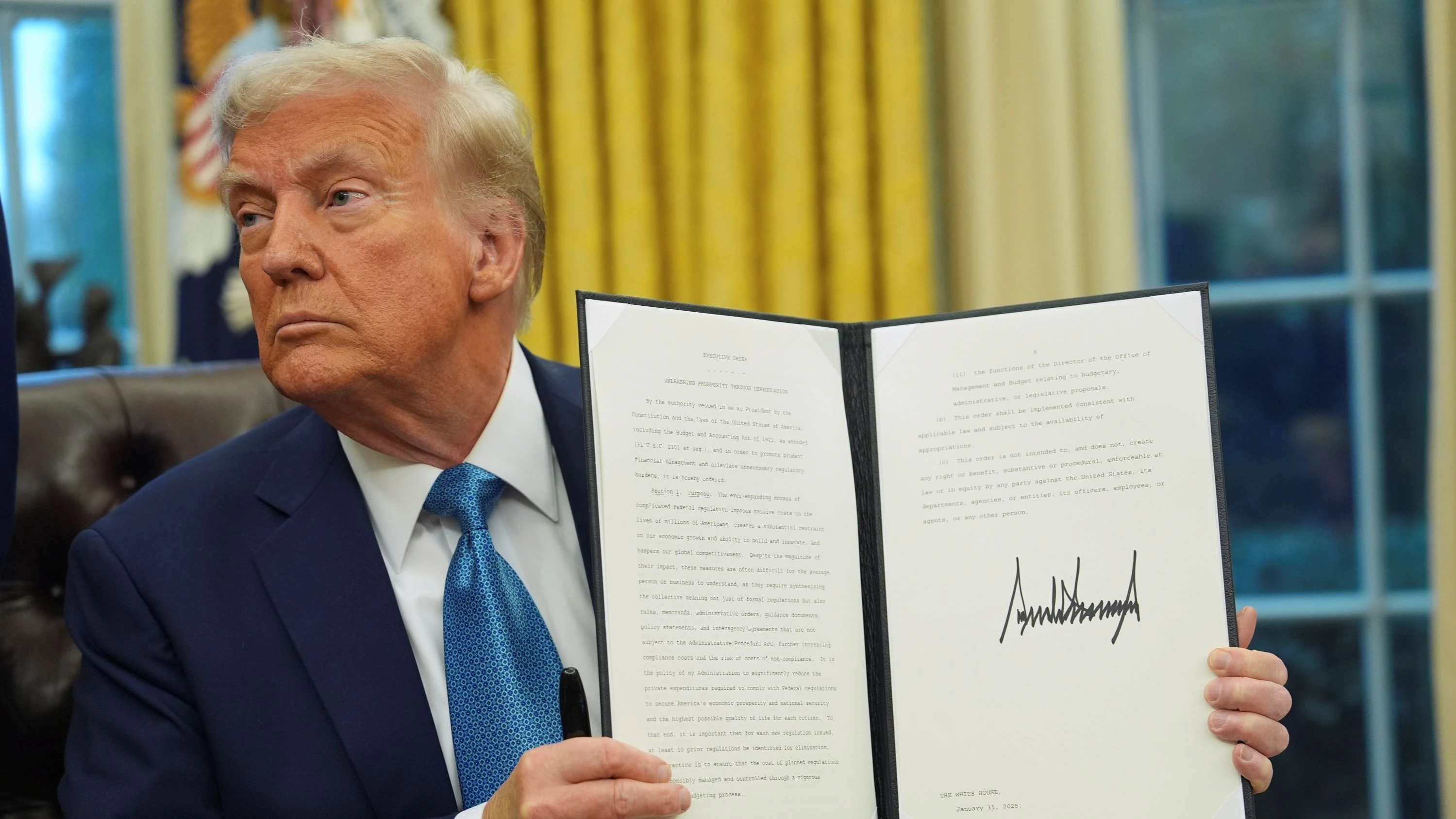 US President Donald Trump holds a signed executive order in the Oval Office of the White House, Jan 31, 2025, in Washington.