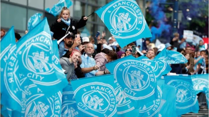 Manchester City fans with flags during the victory parade in Manchester, Britain after winning the Premier League in the 2023/24 season on May 26, 2024.