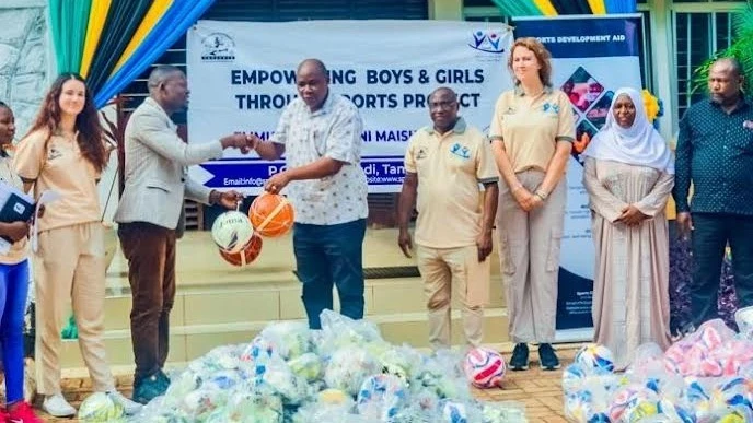 Katibu Tawala Msaidizi Elimu Mkoa wa Lindi, Joseph Mabeyo (katikati), akipokea misaada wa mipira 585 kutoka kwa Mkurugenzi wa Shirika lisilo la kiserikali la Sports Development Aid Ramson, Ramson Lucas