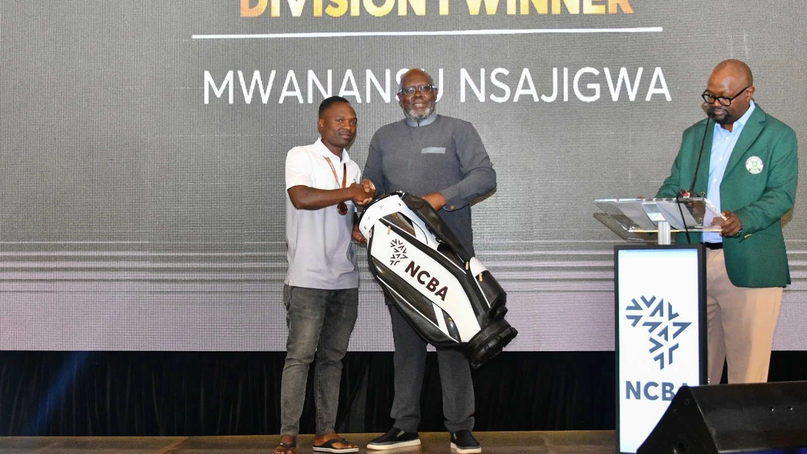 Tanzania’s Nsajigwa Mwansasu (left) presented a gift from NCBA Bank Kenya chairman Isaac Auwondo after emerging as the Division 1 champion of the NCBA Golf Series 2025 Finale in Nairobi at the weekend. 
