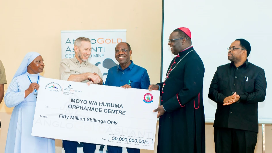 Acting Managing Director of Geita Gold Mining Limited (GGML), Duan Campbell (C), shakes hands with the Geita Regional Commissioner, Martine Shigela (3rd R), after handing over a 50m/- dummy cheque for the Moyo wa Huruma Orphanage in Geita Region.